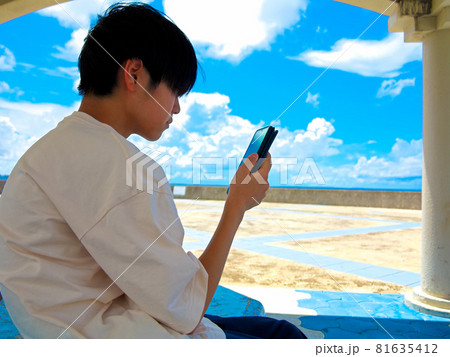 海岸沿いのストリートでスマホを片手にくつろぐ少年 海岸沿いのストリートでスマホを片手にくつろぐ少年 81635412