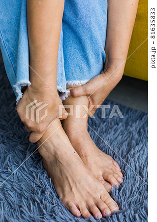 Woman sitting on sofa using hand to hold leg and feeling pain, suffer, hurt and tingling. Concept of Guillain barre syndrome and numb hands disease effect Woman sitting on sofa using hand to hold leg and feeling pain, suffer, hurt and tingling. Concept of Guillain barre syndrome and numb hands disease effect 81635833