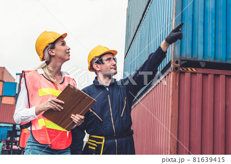 Industrial worker works with co-worker at overseas shipping container yard Industrial worker works with co-worker at overseas shipping container yard 81639415