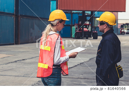 Industrial worker works with co-worker at overseas shipping container yard Industrial worker works with co-worker at overseas shipping container yard 81640566