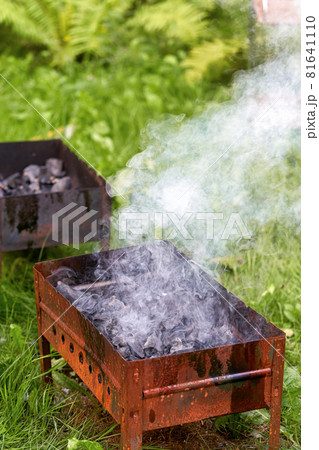 Firing up an old rusty metal barbecue grill, smoke and fire Firing up an old rusty metal barbecue grill, smoke and fire 81641110