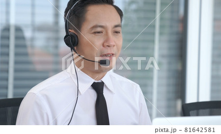 Businessman wearing headset working actively in office Businessman wearing headset working actively in office 81642581