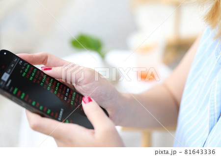 Female hand with smartphone trading stocks online in coffee shop Business concept Female hand with smartphone trading stocks online in coffee shop Business concept 81643336