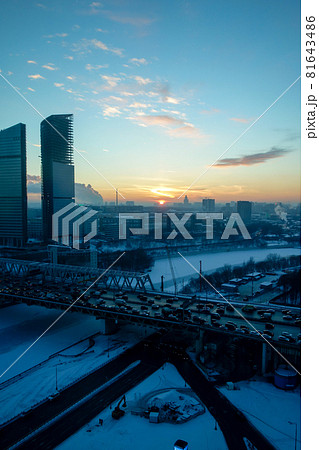 寒い冬のモスクワの街並みと沈みゆく夕日と凍り付いた川 81643486