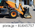 The front part of wheel loader bulldozer with dirty bucket on repair site in town by building. 81645757
