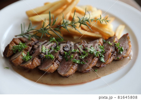 Duck magret confit with chips on wood table 81645808