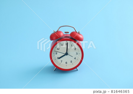 Red retro alarm clock isolated on a blue background Red retro alarm clock isolated on a blue background 81646365