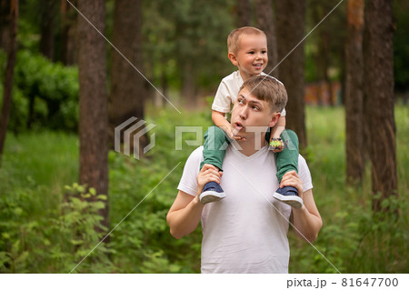 Happy funny kid riding on dads shoulders. Caucasian dad and son playing together 81647700