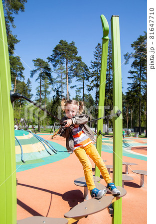little girl climbs the suspension bridge at the playground outdoors little girl climbs the suspension bridge at the playground outdoors 81647710