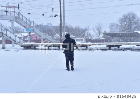 Winter. White snow. A man in a black jacket walks across the square. Winter. White snow. A man in a black jacket walks across the square. 81648428