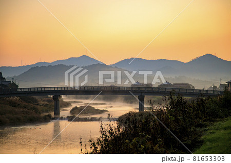 秋の朝焼けの空と川霧流れる空を飛ぶ鵜の群れ 81653303