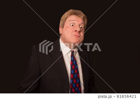 Studio shot of angry senior businessman against dark background 81656421