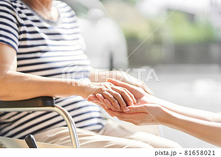 介護士と車椅子に乗る高齢者の手元	 81658021