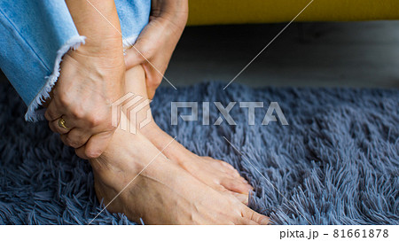 Woman sitting on sofa using hand to hold leg and feeling pain, suffer, hurt and tingling. Concept of Guillain barre syndrome and numb hands disease effect Woman sitting on sofa using hand to hold leg and feeling pain, suffer, hurt and tingling. Concept of Guillain barre syndrome and numb hands disease effect 81661878