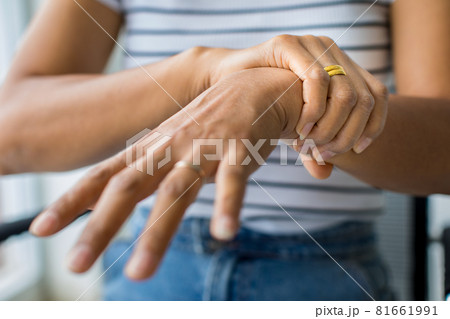 Woman in using hand to hold wrist and stretching fingers. with feeling pain, suffer, hurt and tingling. Concept of Guillain barre syndrome and numb hands disease 81661991