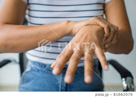 Woman in using hand to hold wrist and stretching fingers. with feeling pain, suffer, hurt and tingling. Concept of Guillain barre syndrome and numb hands disease 81662070