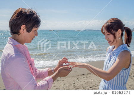 晴れた夏の海辺で指輪を渡すカップル 81662272