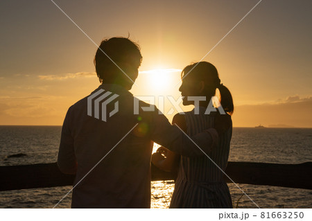 夕暮れの海辺で愛を語るカップル 81663250