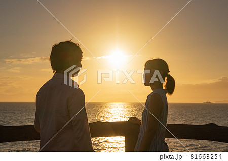 夕暮れの海辺で愛を語るカップル 81663254