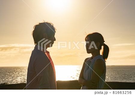 夕暮れの海辺で愛を語るカップル 81663256