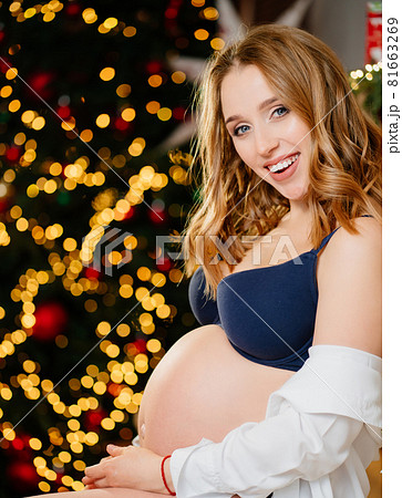 an attractive pregnant woman with a bare tummy near the christmas tree an attractive pregnant woman with a bare tummy near the christmas tree 81663269