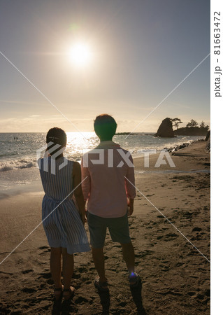 夏の夕日の海辺の若いカップル 81663472