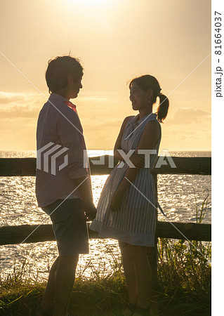 夏の夕暮れの海辺で向かい合うカップル 夏の夕暮れの海辺で向かい合うカップル 81664037