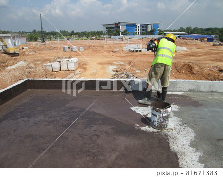 SELANGOR, MALAYSIA -SEPTEMBER, 2014: Construction worker apply layer of bituminous waterproofing at the building roof slab surface. SELANGOR, MALAYSIA -SEPTEMBER, 2014: Construction worker apply layer of bituminous waterproofing at the building roof slab surface. 81671383