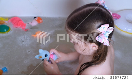 Little girl 3 years old with two ponytails on her head, bathes and washes in the water in the 81673722