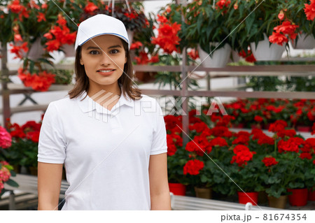 Good-looking young woman working with red flowers. Good-looking young woman working with red flowers. 81674354