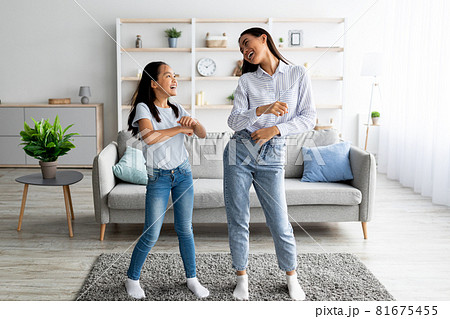 Full length of asian mother dancing to music with her cute daughter at home, having fun together 81675455