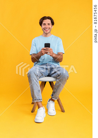 Happy guy using mobile phone at studio 81675456