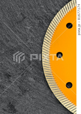 Fragment of a yellow diamond cutting wheel on a dark gray granite background, the concept of stone processing in the interior and construction. Vertical image. 81677174
