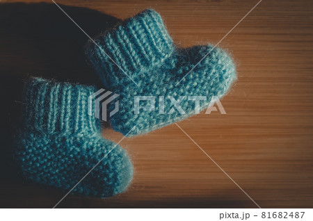 A pair of blue booties for a small child. Early morning, light from the window. 81682487