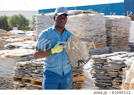 Man holding stone while standing in outdoor warehouse 81690312