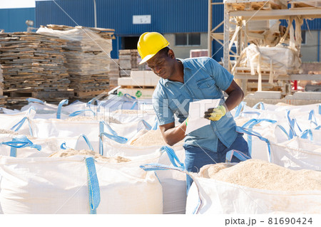 Worker checking quality of building mix at hardware store 81690424