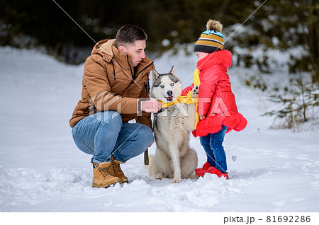 Happy father and little daughter and husky dog in winter forest walking in winter. 81692286