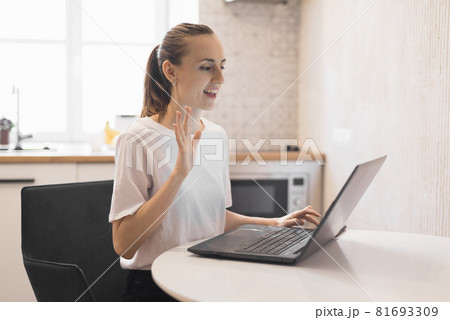 Young woman working on laptop at kitchen. Female freelancer working online Young woman working on laptop at kitchen. Female freelancer working online 81693309