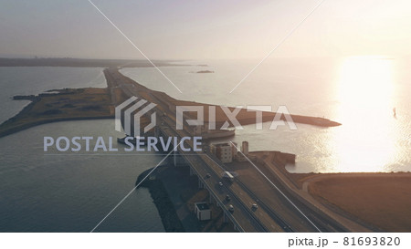 Aerial view of a truck with POSTAL SERVICE infographics driving along the road across the sea Aerial view of a truck with POSTAL SERVICE infographics driving along the road across the sea 81693820