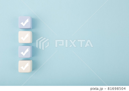 Four checkmarks on light toy blocks against pastel blue background with copy space 81698504