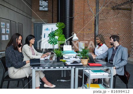 Young and old businesspeople sitting and working at desk in office, cooperation and coworking concept. Young and old businesspeople sitting and working at desk in office, cooperation and coworking concept. 81699412