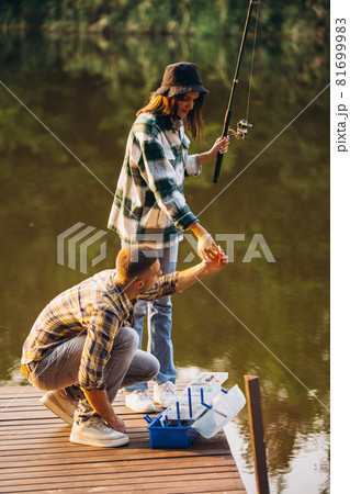 Vertical portrait of young couple fishing on warm summer day in countryside at sunset 81699983