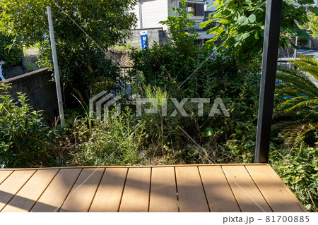 手入れをしていない雑草だらけの荒れ放題の家の庭をテラスから見たところ 81700885