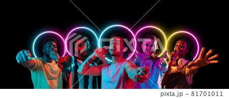 Collage made of multiethnic young people standing together isolated on dark studio background in multicolored neon light with geometric luminescent shape cirlce 81701011
