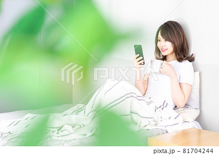 ベッドでスマホを使う若い女性 81704244