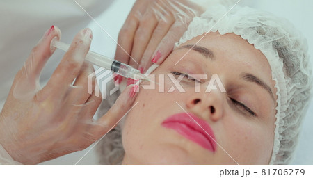 Close-up of beauty injection procedure in modern beauty clinic. injection with syringe into female cheek. Beautician performing mesotherapy and face lifting treatment in beauty salon. Close-up of beauty injection procedure in modern beauty clinic. injection with syringe into female cheek. Beautician performing mesotherapy and face lifting treatment in beauty salon. 81706279
