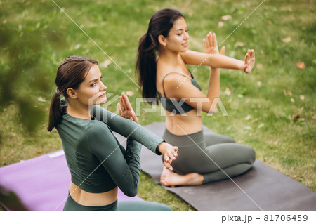 Top back view of two fit girls practising yoga on open air on warm summer day 81706459