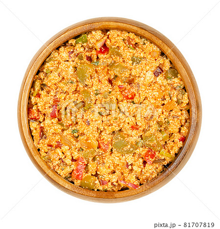 Vegan Liptauer bread spread, in a wooden bowl. Spicy spread, made of crumbled white tofu, red peppers, gherkins, onions and spices. Savory traditional Austrian-Hungarian cuisine. Close-up, from above. 81707819