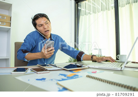 businessman who looks busy negotiating through multiple mobile phones. During the coronavirus disease 2019 epidemic around the world. Working from home businessman who looks busy negotiating through multiple mobile phones. During the coronavirus disease 2019 epidemic around the world. Working from home 81709291