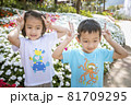 Two children relaxing in a sunny summer garden. A little girl and a little boy are playing in the park. 81709295